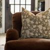 Pillow cover styled on brown armchair in front of window, showcasing living room setting