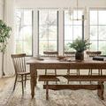 Dining room setting with rug underneath a wooden table, bench, and spindle-back chairs