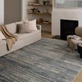 Styled living room setting with rug under sofa and armchair near fireplace