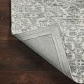 Rug corner flipped up showing grey woven backing and folded edge binding for durability