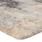 Close-up of thick, plush fibers in gray, cream, and beige tones showing soft, shag texture