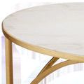 Close-up of white marble top inset into gold frame with curved metal support underneath