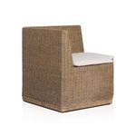 Close-up focusing on woven rattan armrest with beige cushion peeking inside