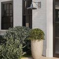 Mariner sconce shown in outdoor setting with landscaping, mounted on building exterior wall