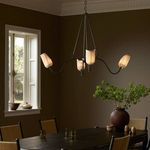 Rafa Chandelier illuminated in dining room setting above wooden table with greenery and window light