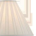 Detail view of ivory fabric lamp shade with vertical pleats and brass finial