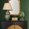 Small natural raffia Pisco Box with clear acrylic lid and champagne gold handle on dark wood cabinet with green walls