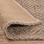 Folded rug underside revealing backing material and thick jute weave profile