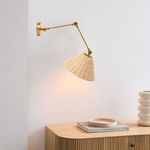 Wall sconce mounted on a white wall above wood dresser with warm light on