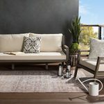 Rug styled on outdoor deck under beige sofa and chair with neutral pillows, black lanterns, and a white watering can