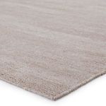 Close-up of light taupe rug showing handwoven PET yarn texture and tightly finished edges.