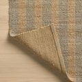 Corner turned over to show rug’s tightly woven natural fiber backing with jute and cotton blend