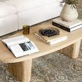 Top view of wood coffee table on rug with books, decorative bowl of blueberries, and amber glass