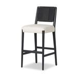 Three-quarter view showing stool's angled legs and woven backrest texture