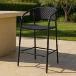 Zola Outdoor Bar Stool styled on a patio with tiled flooring and green lawn background