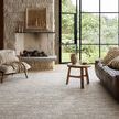 Rug in bright room with natural stone fireplace, wood furniture, and large industrial-style windows