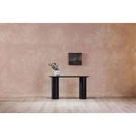 Painting hanging above sleek black console table in simple interior setting