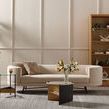 Sofa styled in a room setting with grey rug, decorated coffee tables, plants, and wooden shelving