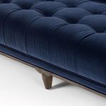 Close-up detail of tufted navy velvet seat cushion and midcentury style wooden leg