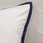 Corner angle of white pillow featuring navy blue piping showing smooth bamboo sateen texture