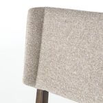 Close-up detail of chair's angled wing back edge with light beige textured fabric