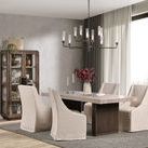 Dining room setup with table surrounded by beige slipcovered chairs and a modern chandelier