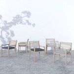 Five chairs in different cushion colors grouped outdoors on cobblestone surface with light tree shadows