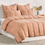 Angled perspective of quilted set on bed showing fabric texture and stitch lines on side pleat