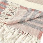 Close-up of fringed edge highlighting linen texture and weave detail in striped cream, red, and gray