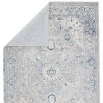 Rug partially folded back showing the light gray backing and pile thickness from a top-down perspective