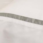 Close-up of white bamboo sateen fabric with gray trim detail highlighting smooth texture