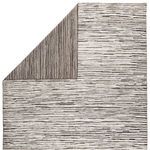 Corner view revealing the rug's reversible back with a denser dark gray striped pattern