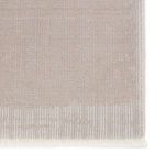 Close-up of rug corner showing fringe detail and linear pattern in taupe and light gray