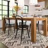 Slightly angled view of rug extending under dining table with black chairs on dark wood floor