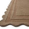 Close-up of rug’s scalloped corner and textured striped border in warm earth tones
