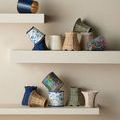 Multiple assorted chandelier shades in various colors and patterns displayed on white shelves