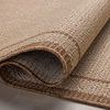 Edge of rug rolled up to reveal flexible polypropylene material and stitched edging