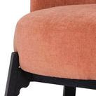 Close-up of textured nectarine upholstery and carefully carved black wooden leg detail on chair