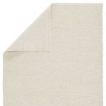 Top view of rug corner folded over, showing woven backside in beige and ivory braided pattern
