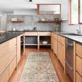 Runner sized taupe and brick rug in modern kitchen with wood cabinets and concrete backsplash