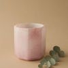 Side view of pink alabaster octagonal vase styled with small green eucalyptus branch on beige background