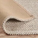 Back side of Chevron jute rug curled up revealing woven backing and binding