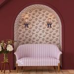 Room setting with wallpaper in an arched alcove behind a pink striped curved sofa and red walls