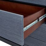 Open drawer showing wooden interior and metal drawer slide on navy blue textured dresser.