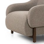 Close-up view of front rounded armrest blending into the cushioned seat and wooden legs