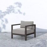 Sonoma Faye Ash Outdoor Chair shown on stone patio with shadowed white wall background