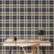 Navy and gold plaid wallpaper in home office setting with wooden desk, chair, and black desk lamp
