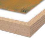 Close-up of painting’s textured canvas and artist signature with light wood floating frame corner visible