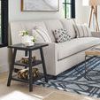 Black square end table styled beside a beige sofa on patterned rug in a bright living room
