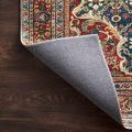 Corner of Layla rug folded back to reveal gray non-slip backing on dark wood floor